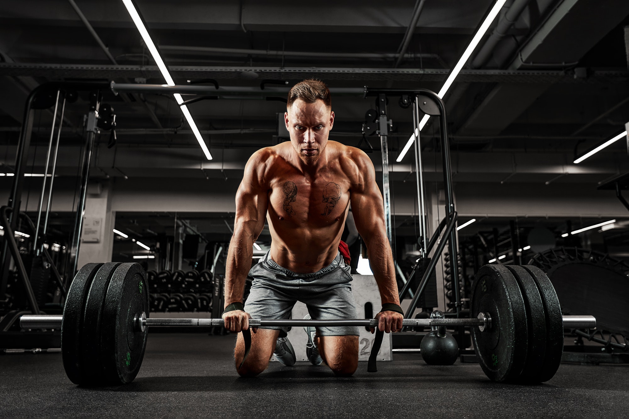 Atmospheric photo of an athlete with a barbell in a dark room, concentration, preparation for work